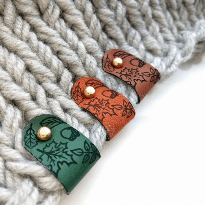 Koženková cedulka Podzimní listí – zelená, zlatý nýt, 70 × 20 mm
